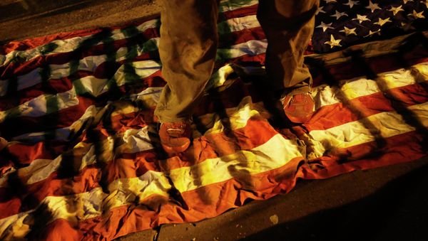 A demonstrator steps on an American flag during a demonstration following the grand jury decision in the Ferguson, Missouri shooting of Michael Brown, in Oakland, California - Sputnik International