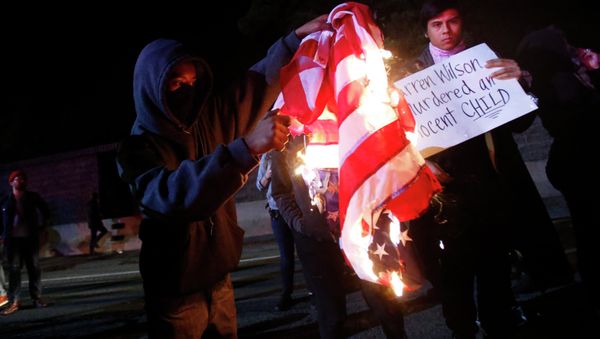 A protester burns an American flag on Highway 580 during a demonstration following the grand jury decision in the Ferguson, Missouri shooting of Michael Brown, in Oakland, California A protester burns an American flag on Highway 580 during a demonstration following the grand jury decision in the Ferguson, Missouri shooting of Michael Brown, in Oakland, California - Sputnik International