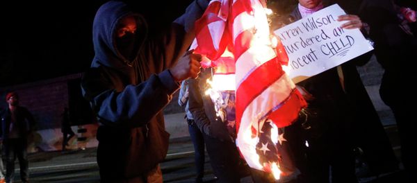 A protester burns an American flag on Highway 580 during a demonstration following the grand jury decision in the Ferguson, Missouri shooting of Michael Brown, in Oakland, California A protester burns an American flag on Highway 580 during a demonstration following the grand jury decision in the Ferguson, Missouri shooting of Michael Brown, in Oakland, California - Sputnik International