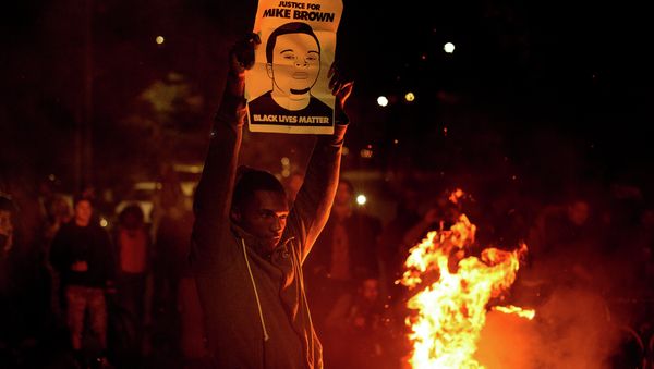 A demonstrator holds a protest sign in Oakland - Sputnik International