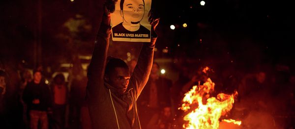 A demonstrator holds a protest sign in Oakland A demonstrator holds a protest sign in Oakland - Sputnik International