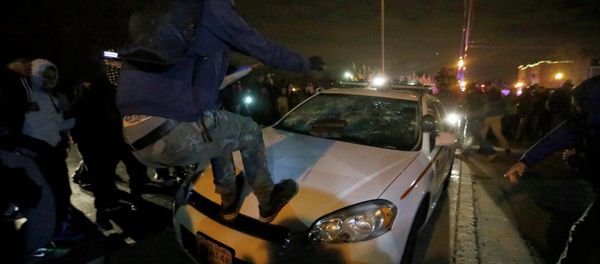 Protesters vandalize a police car outside the Ferguson Police Department in Ferguson, Missouri, after a grand jury returned no indictment in the shooting of Michael Brown - Sputnik International
