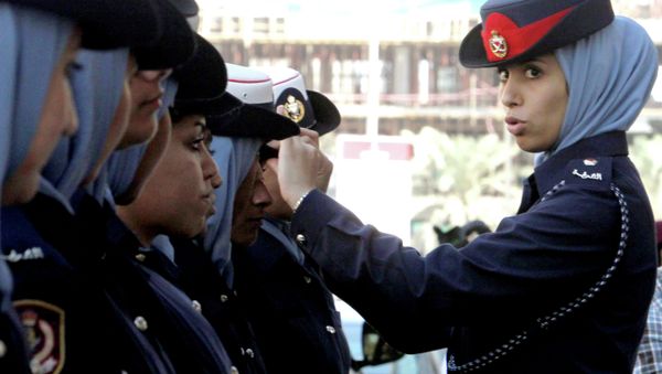 A Bahraini policewoman adjusts a colleague's hat outside the Manama, Bahrain - Sputnik International