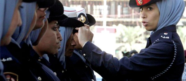 A Bahraini policewoman adjusts a colleague's hat outside the Manama, Bahrain A Bahraini policewoman adjusts a colleague's hat outside the Manama, Bahrain - Sputnik International