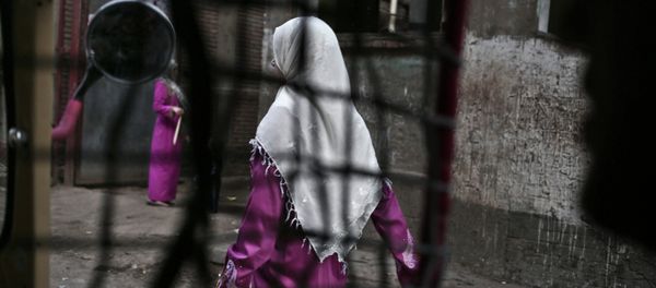 An Egyptian woman seen from a motorized rickshaw walks on a street, near the home of 13-year-old Sohair el-Batea who died undergoing the procedure of female genital mutilation - Sputnik International