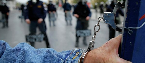 A protester wears handcuffs as he stands in front of riot police following a march during a 24-hour general strike in central Athens November 27, 2014 - Sputnik International
