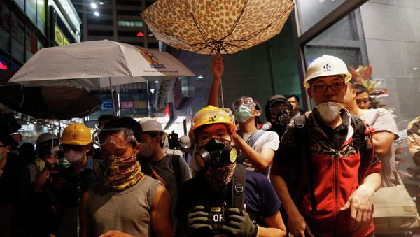 Protesters protect themselves from being sprayed with tear spray during a confrontation with riot police at Mongkok shopping district in Hong Kong Protesters protect themselves from being sprayed with tear spray during a confrontation with riot police at Mongkok shopping district in Hong Kong - Sputnik International