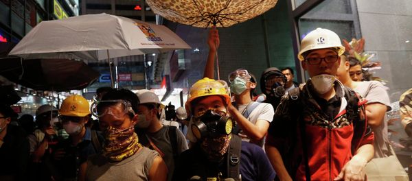 Protesters protect themselves from being sprayed with tear spray during a confrontation with riot police at Mongkok shopping district in Hong Kong Protesters protect themselves from being sprayed with tear spray during a confrontation with riot police at Mongkok shopping district in Hong Kong - Sputnik International