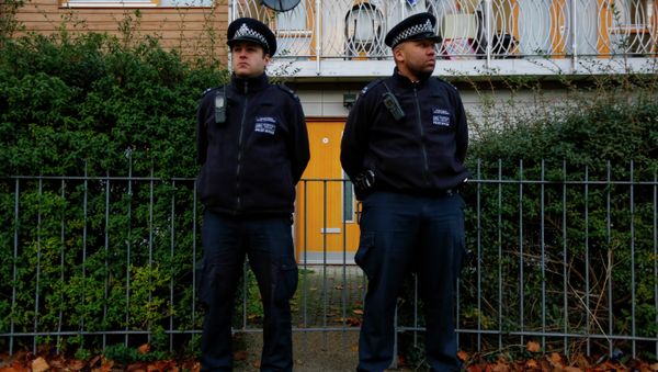 Police stand guard outside a South London  - Sputnik International