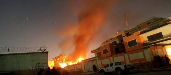 Afghan security forces keep watch while smoke and fire rise from a foreign aid guest house after a Taliban attack in the Afghan capital of Kabul November 29, 2014 - Sputnik International