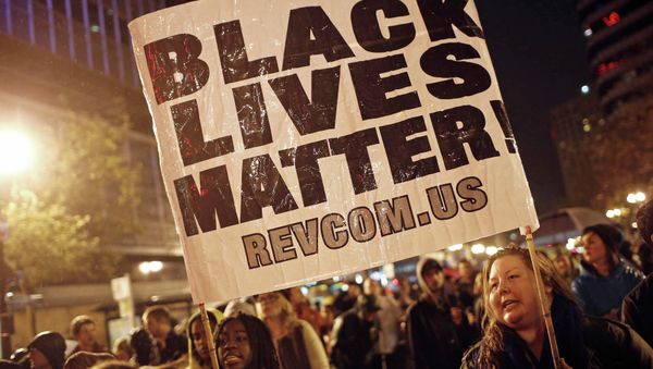 Protesters hold a sign during a march against the New York City grand jury decision to not indict in the death of Eric Garner, in Oakland, California December 3, 2014. Protesters hold a sign during a march against the New York City grand jury decision to not indict in the death of Eric Garner, in Oakland, California December 3, 2014. - Sputnik International