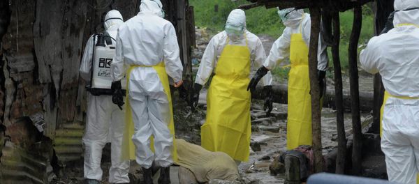 Health workers wearing protective clothing prepare to carry an abandoned dead body presenting with Ebola symptoms Health workers wearing protective clothing prepare to carry an abandoned dead body presenting with Ebola symptoms - Sputnik International