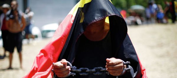 A protester demanding human rights for Australia's Aboriginal community wears symbolic shackles as he is draped in the Aboriginal flag. - Sputnik International