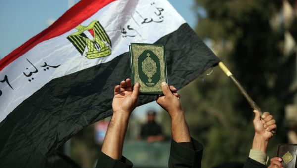 An Egyptian man holds up the a copy of Quran - Sputnik International