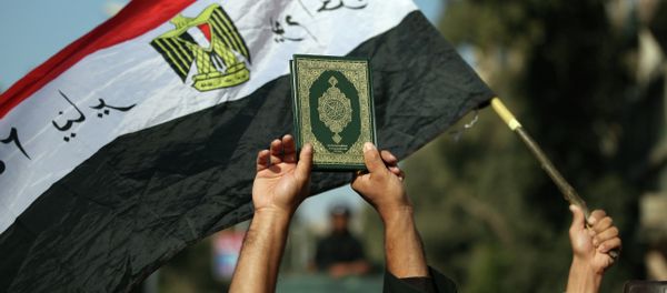 An Egyptian man holds up the a copy of Quran - Sputnik International
