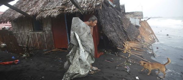 A Filipino man carries a dirty plastic sheet from his house after strong waves from Typhoon Hagupit - Sputnik International