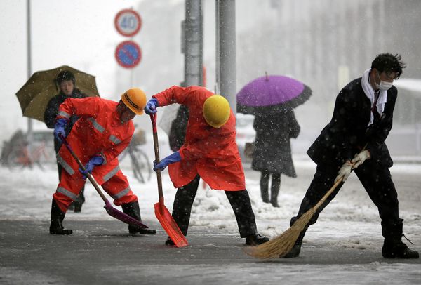 Railway station workers shove snow from the street in Yokohama, Japan, Saturday. - Sputnik International
