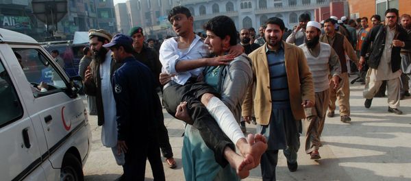 A man carries a student, who was injured during an attack by Taliban gunmen on the Army Public School, after he received treatment at a hospital in Peshawar, December 16, 2014 - Sputnik International