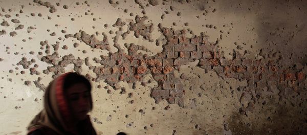 A local reporter walks past a damaged wall - Sputnik International