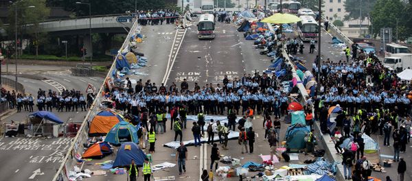 Police officers stand in a line as they prepare to clear tents outside Hong Kong's Government complex in Hong Kong - Sputnik International