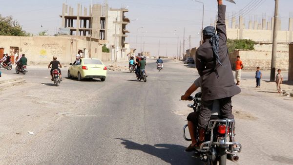 A man holds up a knife as he rides on the back of a motorcycle in Northern Syria. A man holds up a knife as he rides on the back of a motorcycle in Northern Syria. - Sputnik International