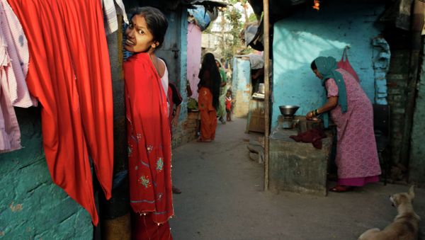 An Indian woman reacts to the camera as another sells meat in a narrow alley at a slum area in New Delhi, India, Tuesday, May 21, 2013 - Sputnik International