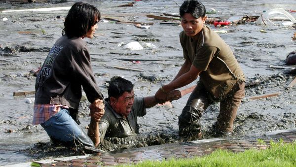 Acehnese youths try to pull a man to higher ground through a flooded street a moment after tsunami strike in the provincial capital of Banda Aceh, Aceh province, Indonesia - Sputnik International