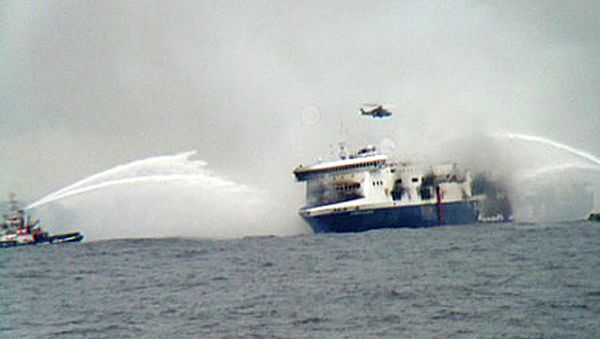 A rescue helicopter flies over the burning car ferry Norman Atlantic as fire fighting tug boats douche the vessel in south Adriatic sea - Sputnik International