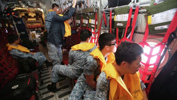 Republic of Singapore Air Force (RSAF) personnel survey the waters onboard a C-130 Hercules during a Search and Locate operation for the missing AirAsia QZ8501 aircraft over an undisclosed search area December 29, 2014 - Sputnik International