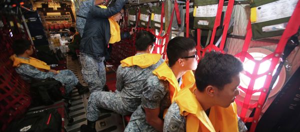 Republic of Singapore Air Force (RSAF) personnel survey the waters onboard a C-130 Hercules during a Search and Locate operation for the missing AirAsia QZ8501 aircraft over an undisclosed search area December 29, 2014 - Sputnik International