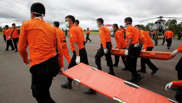 Indonesian Search and Rescue crews walk out to meet a helicopter carrying the bodies of two AirAsia passengers recovered from the sea, at Iskandar airport in Pangkalan Bun, Central Kalimantan, December 31, 2014 - Sputnik International