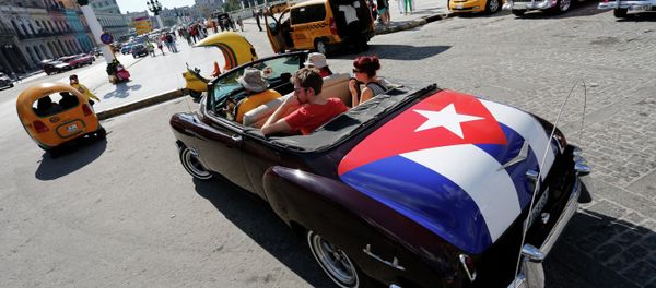In this Dec. 18, 2014 file photo, tourists take a ride in a classic American convertible car with the Cuban national flag painted on the trunk, in Havana, Cuba In this Dec. 18, 2014 file photo, tourists take a ride in a classic American convertible car with the Cuban national flag painted on the trunk, in Havana, Cuba - Sputnik International