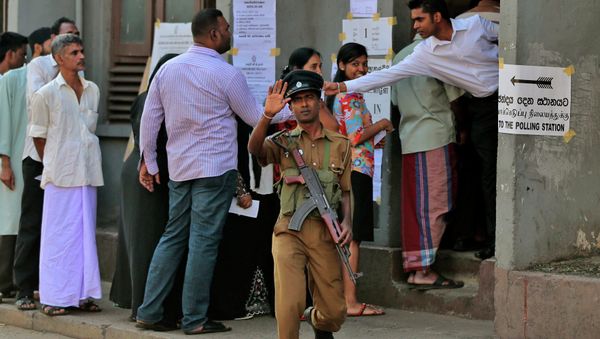 A Sri Lankan police officer gestures to the photographer demanding not to take photographs as people stand in a queue to cast their votes during the presidential elections in Colombo, Sri Lanka, Thursday, Jan. 8, 2015 A Sri Lankan police officer gestures to the photographer demanding not to take photographs as people stand in a queue to cast their votes during the presidential elections in Colombo, Sri Lanka, Thursday, Jan. 8, 2015 - Sputnik International