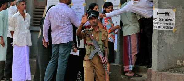 A Sri Lankan police officer gestures to the photographer demanding not to take photographs as people stand in a queue to cast their votes during the presidential elections in Colombo, Sri Lanka, Thursday, Jan. 8, 2015 - Sputnik International