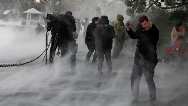 Members of the press, including NBC's Evan Dixon (R), face the blowing snow caused by Marine One as it lands on the South Lawn. - Sputnik International