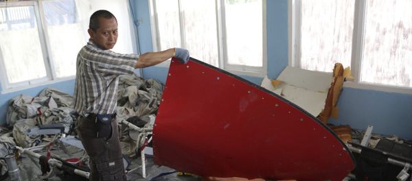 A member of Indonesian Search and Rescue Agency holds a piece which Indonesian Air Force confirmed as from AirAsia Flight 8501, at Disaster Victim Identification room in Pangkalan Bun, Indonesia, Friday, Jan. 9, 2015 - Sputnik International