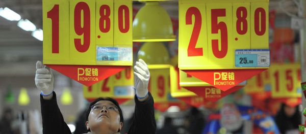 An employee adjusts a price tag at a supermarket in China - Sputnik International