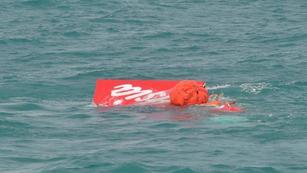 Part of the tail of AirAsia QZ8501 floats on the surface after being lifted as Indonesian navy divers conduct search operations for the black box flight recorders and passengers and crew of the aircraft, in the Java Sea January 10, 2015. - Sputnik International