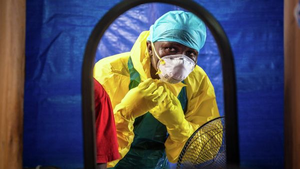 Healthcare worker dons in protective gear before entering an Ebola treatment center in the west of Freetown, Sierra Leone - Sputnik International