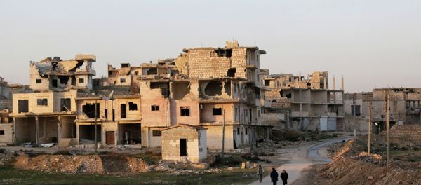 Residents walk near damaged buildings in Maaret al-Naaman town in Idlib province January 14, 2015 - Sputnik International