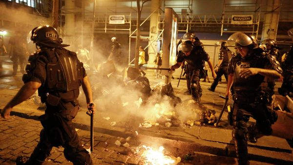 Riot police officers walk past garbage lit on fire by protestors during a demonstration against the increase on bus fares in Rio de Janeiro, Brazil, Friday, Jan. 9, 2015 Riot police officers walk past garbage lit on fire by protestors during a demonstration against the increase on bus fares in Rio de Janeiro, Brazil, Friday, Jan. 9, 2015 - Sputnik International
