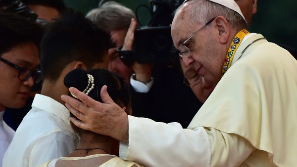Pope Francis (R) reaches out to a child during his visit to the University of Santo Tomas in Manila - Sputnik International