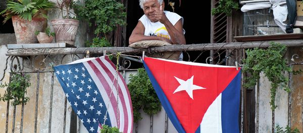 A Cuban gives the thumbs up from his balcony decorated with the US and Cuban flags in Havana - Sputnik International