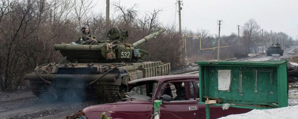 A man rides a Ukrainian tanks past a damaged vehicle in the village of Tonenke, some 5 kilometers from the Donetsk airport - Sputnik International