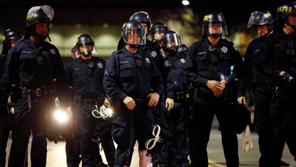 A police officer looks into the crowd, after he was hit on the leg with paint thrown by protesters during an evening demonstration against police violence, in Oakland, California December 13, 2014. A police officer looks into the crowd, after he was hit on the leg with paint thrown by protesters during an evening demonstration against police violence, in Oakland, California December 13, 2014. - Sputnik International