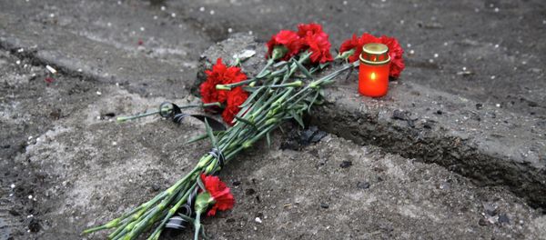A candle and flowers are layed at a bus stop where 13 people were killed in a trolleybus shelling in Donetsk, eastern Ukraine, on January 22, 2015 - Sputnik International