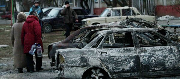 People look at burned out cars as they walk along a street in the southern Ukrainian city of Mariupol - Sputnik International