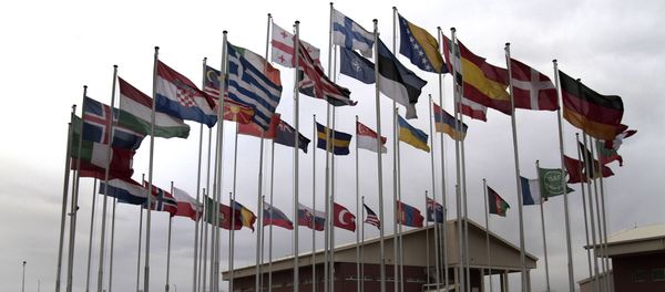 NATO Soldiers walk under country member flags at a NATO base at Kabul International Airport in Kabul, Afghanistan - Sputnik International