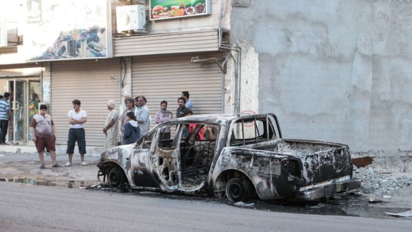 Men stand near a burned vehicle in the eastern town of al-Awamiya, Saudi Arabia Men stand near a burned vehicle in the eastern town of al-Awamiya, Saudi Arabia - Sputnik International