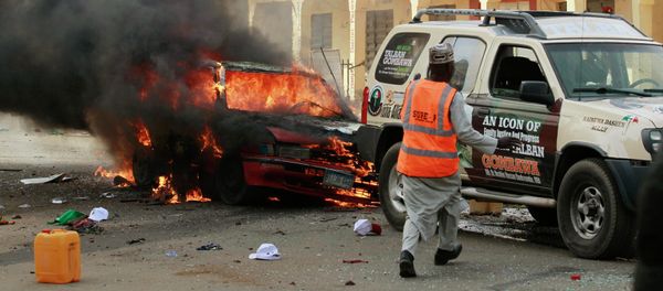 A man rushes towards a vehicle next to a burning car at the scene of a bomb explosion in Gombe A man rushes towards a vehicle next to a burning car at the scene of a bomb explosion in Gombe - Sputnik International